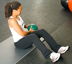 Chelsea Cooper demonstrating Seated Oblique Twists with Medicine Ball. - Copyright – Stock Photo / Register Mark