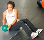 Chelsea Cooper demonstrating Seated Oblique Twists with Medicine Ball. - Copyright – Stock Photo / Register Mark