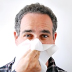 Man blowing his nose into a tissue. - Copyright – Stock Photo / Register Mark