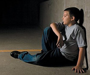 A depressed preteen sitting with his back to a wall. - Copyright – Stock Photo / Register Mark