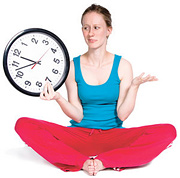 A woman dressed for exercising holding a clock in one hand. - Copyright – Stock Photo / Register Mark
