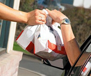A fast food worker hands two bags of food to a customer at a drive-thru window. - Copyright – Stock Photo / Register Mark