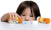A young girl emptying a pill bottle onto a counter top. - Copyright – Stock Photo / Register Mark
