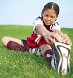A young female soccar player sitting and stretching her legs. - Copyright – Stock Photo / Register Mark