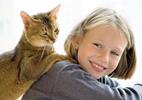 A young girl poses with her cat laying on her back. - Copyright – Stock Photo / Register Mark