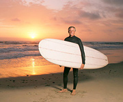 A middle aged man stands holding his surfboard in front the ocean. - Copyright – Stock Photo / Register Mark