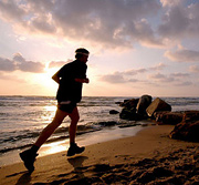 A middle aged man runs along a beach at sunset. - Copyright – Stock Photo / Register Mark