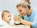 A young mother spoon feeds her baby. - Copyright – Stock Photo / Register Mark