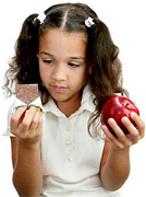 A young girl tries to decide between a candy bar and an apple. - Copyright – Stock Photo / Register Mark