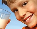 Boy smiles while holding glass of milk. - Copyright – Stock Photo / Register Mark