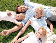 Family of four laying on the grass together. - Copyright – Stock Photo / Register Mark