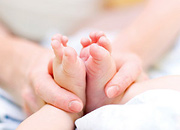 An infant's feet being massaged. - Copyright – Stock Photo / Register Mark