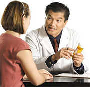 A pediatrician explains the effect of a bottle of pills in his hands to a mother. - Copyright – Stock Photo / Register Mark