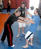 A training kickboxer performs knee-kick into a practice bag held by his sparring partner. - Copyright – Stock Photo / Register Mark