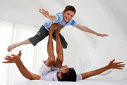 A father using his feet to suspend his young son in the air. - Copyright – Stock Photo / Register Mark