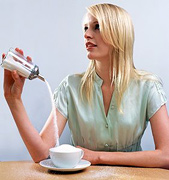 Woman overfilling a coffee cup with sugar. - Copyright – Stock Photo / Register Mark