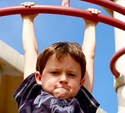 Child hanging from a jungle-gym. - Copyright – Stock Photo / Register Mark